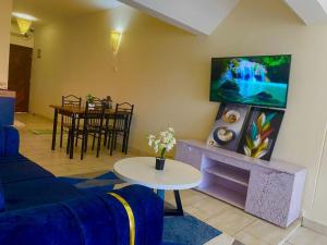 ein Wohnzimmer mit einem Sofa und einem TV an der Wand in der Unterkunft Beachfront bliss villa in Diani Beach