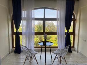 Zimmer mit einem Tisch und Stühlen sowie einem großen Fenster in der Unterkunft Beachfront bliss villa in Diani Beach