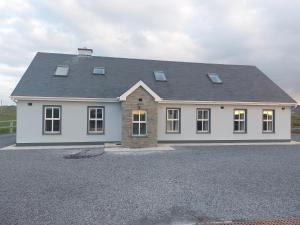 a white house with a gray roof on a driveway at Mountain Aven Guest House in Doolin