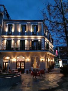 a building with a balcony and tables and chairs at Diethnes in Larisa