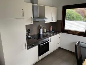 a kitchen with white cabinets and a sink and a window at Henneliebe am Hennesee in Meschede