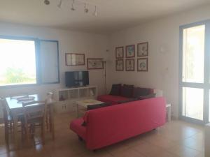 ein Wohnzimmer mit einem roten Sofa und einem Tisch in der Unterkunft Maldive del Salento - Sandalo in Marina di Pescoluse