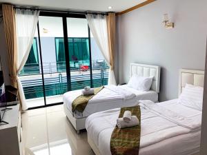 two beds in a room with a balcony at โรงแรม ทรี บริดจ์ โฮเทล in Nan