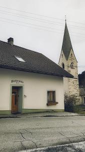 een wit gebouw met een kerktoren met een deur bij Ferienwohnung Biohof Untermar in Obervellach