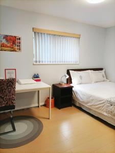 a bedroom with a bed and a desk and a window at Llt Fraser HomeAway in Vancouver