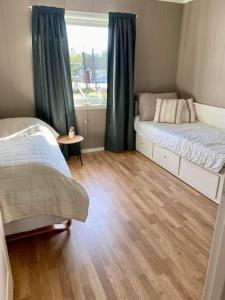 Habitación pequeña con 2 camas y ventana en Leilighet sentralt på Senja, en Silsand