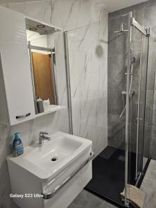 uma casa de banho branca com um lavatório e um chuveiro em Apartman Lavanda em Krapina