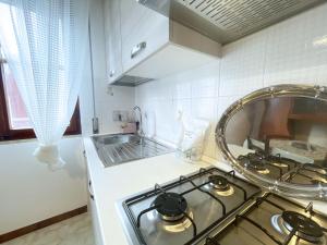 uma cozinha com uma placa de fogão e um lavatório em Casa Diana - ArgonautiVacanze em Porto Azzurro