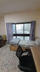 a bedroom with a bed and a chair in front of a window at ADMFHR5 in Abu Dhabi