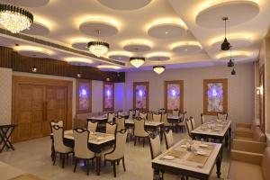 a dining room with tables and chairs and chandeliers at The Velvista Hotel in Muzaffarnagar