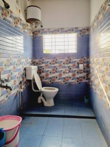 baño con aseo y pared de azulejos azules en Upasana Homestay, en Dibrugarh