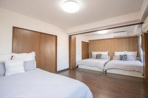 - une chambre avec 2 lits et des draps blancs dans l'établissement Walk to Higashi-Nakano sta. COB3, à Tokyo