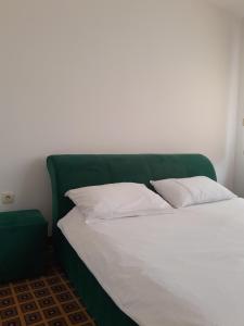 a bed with a green headboard and white pillows at Hotel PEKING in Sarajevo