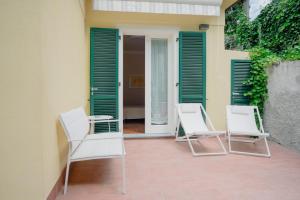 Duas cadeiras brancas num pátio com persianas verdes em Fiordarancio Room Rental em Monterosso al Mare