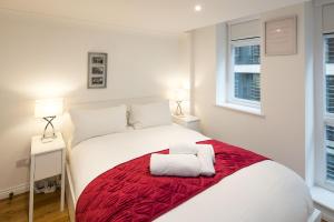 a bedroom with a white bed with a red blanket at 1BD Modern City Oasis: Near London Attractions in London