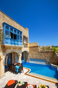 a villa with a swimming pool and a house at Carini Farmhouses in Għarb