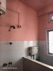Suryalaxmi guest house في غاواهاتي: حمام بجدران وردية ومرحاض ونافذة