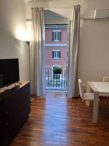 a living room with a table and a television and a table and a window at La casa di Monica appartamento Ostiense Roma in Rome