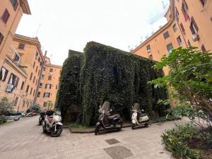 La casa di Monica appartamento Ostiense Roma في روما: ثلاث دراجات نارية متوقفة أمام تحوط أخضر