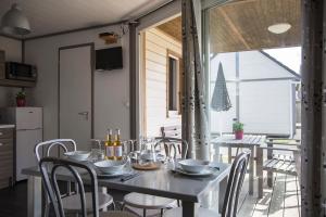 a dining table and chairs in a kitchen with a window at Les Tourelles Village de vacances in Asnelles