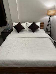białe łóżko z czarnymi poduszkami w sypialni w obiekcie La Serene Inn w mieście Arambol