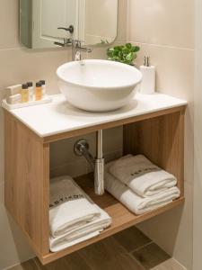 La salle de bains est pourvue d'un lavabo sur une étagère et de serviettes. dans l'établissement ASTIKON Xenofontos Suites, à Athènes