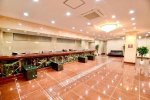 a large lobby with a long bar with plants at Himeji Ekimae Universal Hotel Minamiguchi in Himeji