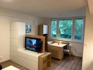 een woonkamer met een tv, een bureau en een tafel bij Útulný byt pro odpočinek i práci in Kutná Hora