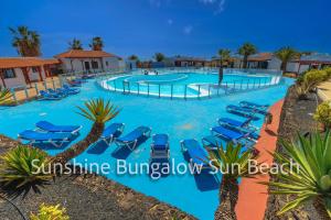un complejo con piscina con sillas azules y palmeras en Sunshine Bungalow Sun Beach, en Caleta de Fuste