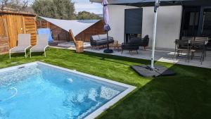 a backyard with a swimming pool with chairs and an umbrella at Gîtes Domaine de la chapelle in Roquefort-les-Pins