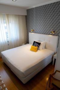 a large white bed with a yellow pillow on it at Belem Hotel in Pombal +28 photos