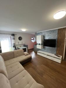 a living room with a couch and a flat screen tv at Holiday Apartments in Krynica Zdrój