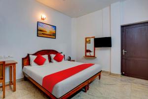 1 dormitorio con 1 cama grande con almohadas rojas en OYO Flagship 81056 Poptavern Heritage en Kovalam