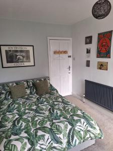 a bedroom with a bed with a green and white comforter at Todmorden Bed & Breakfast - The Toothless Mog in Walsden