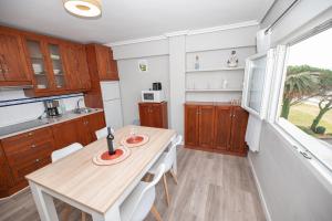 eine Küche mit Holzschränken und einem Tisch mit weißen Stühlen in der Unterkunft EL EMBARCADERO in Pedreña