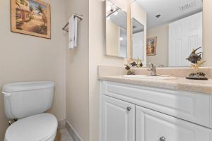 a bathroom with a toilet and a sink and a mirror at Perdido Sun 512 in Perdido Key