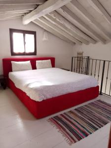un letto rosso in una camera bianca con finestra di Casa San Simon a Massa
