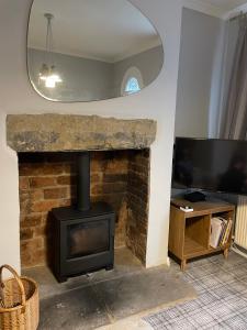 a living room with a stone fireplace and a television at Cosy 1BD Heritage Cottage in Saltaire, Shipley in Shipley