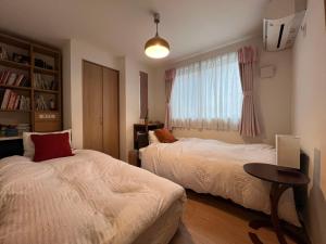 a bedroom with two beds and a window at Uhome Ikebukuro Villa 2 in Tokyo