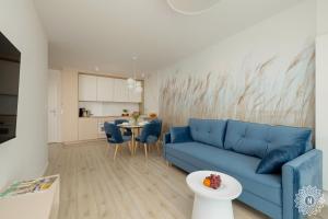 a living room with a blue couch and a table at Seaside Apartamenty WHITEBLUE I Kołobrzeg SAUNA & FITNESS & BAWIALNIA DLA DZIECI & ROWEROWNIA - w cenie pobytu in Kołobrzeg