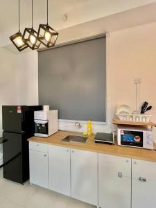 eine Küche mit einer Spüle und einem schwarzen Kühlschrank in der Unterkunft Urban Suite 3R2B 8Pax Georgetown in Jelutong