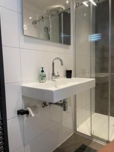 a white bathroom with a sink and a shower at Amsterdam Beach Home 46 in Zandvoort