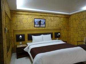 1 dormitorio con 1 cama grande y pared amarilla en Hotel One Karachi en Karachi