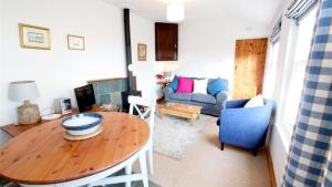 Mulberry Hill Cottage في Nicholaston: غرفة معيشة مع طاولة وأريكة