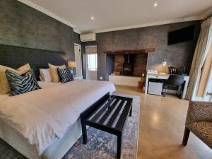 Dormitorio con cama grande y banco en Plumwood Inn - Solar Power en Franschhoek