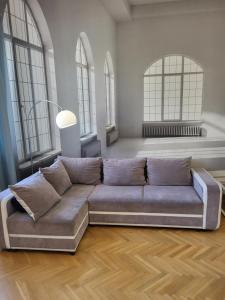 een woonkamer met een bank in een kamer met ramen bij Novo Mundo in Warschau