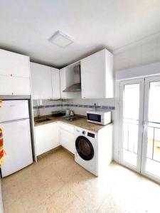 cocina con armarios blancos y lavadora en Sol Centro Apartment B, en Sevilla