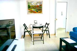 sala de estar con mesa, sillas y sofá azul en Sol Centro Apartment B, en Sevilla