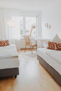 1 Schlafzimmer mit 2 Betten, einem Stuhl und einem Fenster in der Unterkunft Buchnas Landhotel Saarschleife in Mettlach
