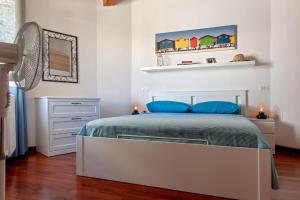a white bedroom with a bed with blue pillows at CASA FELICITA' in Livorno